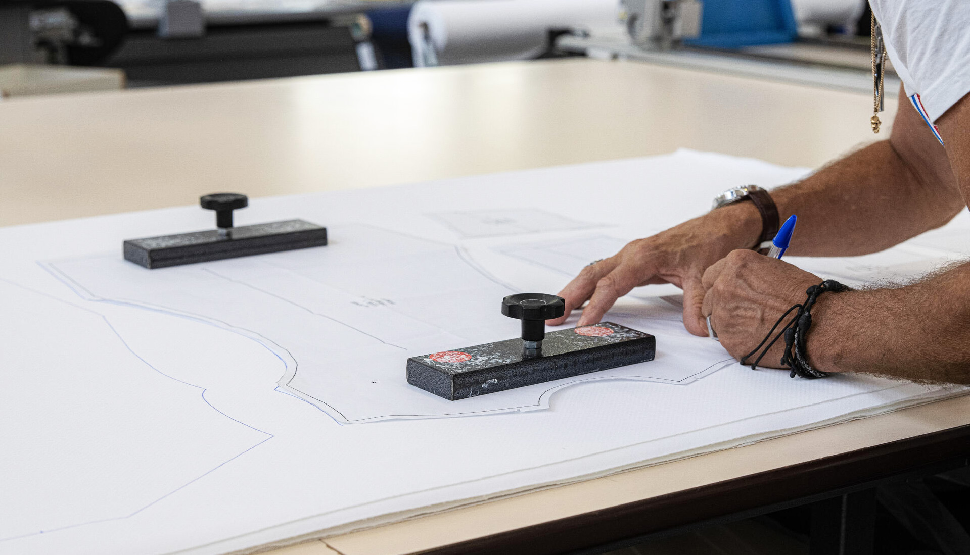 Person marking fabric patterns on a worktable