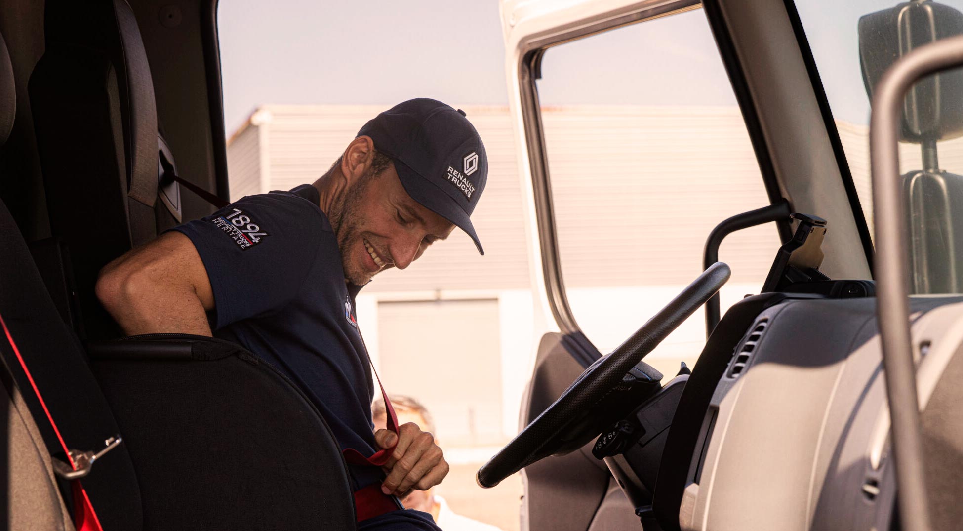 Man wearing Le Coq Sportif cap. Sitting in a truck.