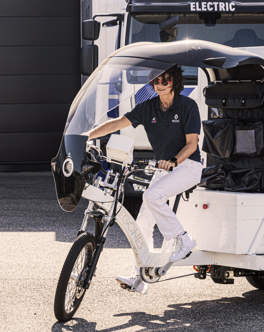 Woman wearing Le Coq Sportif. Riding a bike.