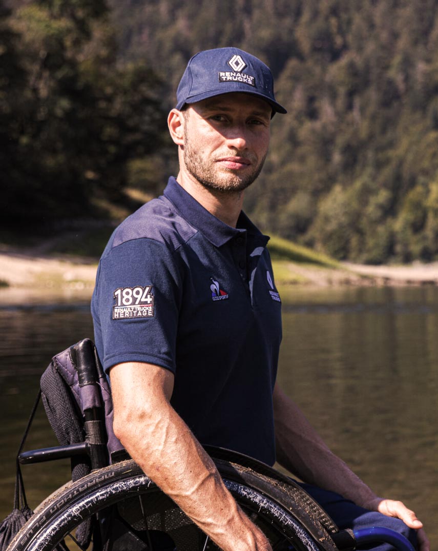 A man in a wheelchair wearing a Le Coq Sportif polo-shirt.